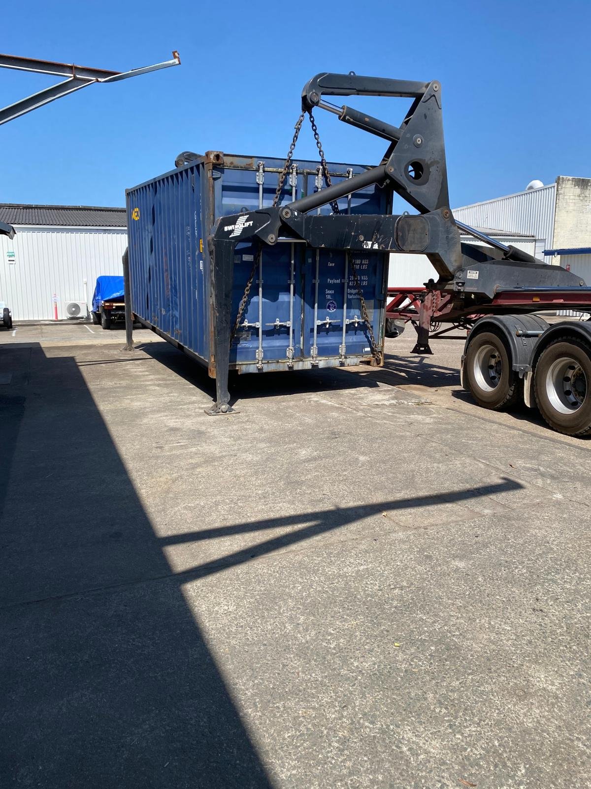 Shipping container lifted by swinglift trailer